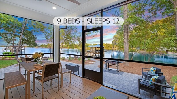 A modern room with large windows overlooking a lake, featuring 9 beds and 12 sleeping areas. - Hanesbee Escape w/Beach, Hot Tub & Optional Boat Rental (Mooresville)