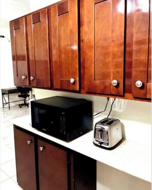 Kitchen area with a microwave and toaster, featuring cabinets with round handles.