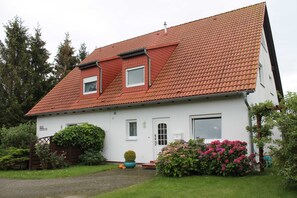 A two-story house with a red-tiled roof, a front door, and a small window. - 3 R-Fewo Smutje - Haus Fiedor in the seaside resort of Zempin (Zempin)