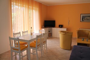 A room with a dining table, chairs, a sofa, a television, and a radiator. - 3 R-Fewo Smutje - Haus Fiedor in the seaside resort of Zempin (Zempin)