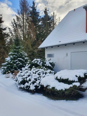A snow-covered building with a sign reading 'Haus FIEDOR' and a garage door.