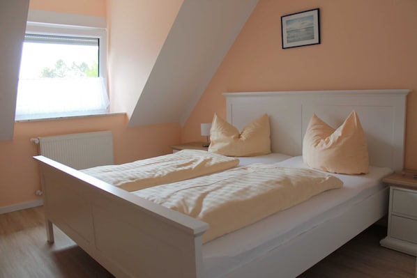 A bedroom with a bed, two bedside tables, a nightstand, a window, and a radiator. - 3 R-Fewo Smutje - Haus Fiedor in the seaside resort of Zempin (Zempin)