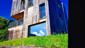 A modern two-story building with a wooden facade and large windows. - Modern, idyllic vacation home with breathtaking panoramic views (Gaschurn)