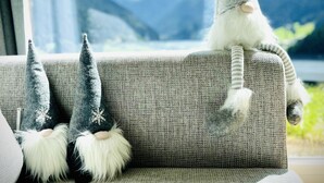 A sofa with three gnome decorations and a view of mountains through a window. - Modern, idyllic vacation home with breathtaking panoramic views (Gaschurn)