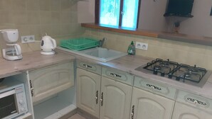 Una cucina con piano cottura a gas, macchina da caffè, scolapiatti e una finestra vista.