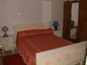 A bedroom with a single bed, a nightstand, a lamp, a dresser, and a mirror. - Country House (Montjay)