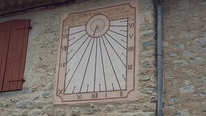 Un meridiano solare su un muro di pietra con numeri romani e testo in francese.