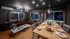 Un comedor moderno con una mesa de madera lista para una comida, rodeado de sofás y sillones de cuero.
