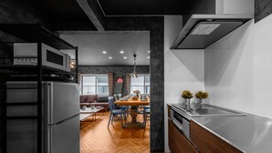 Una cocina moderna con suelo de parqué, electrodomésticos de acero inoxidable y un comedor con mesa y sillas redondas.
