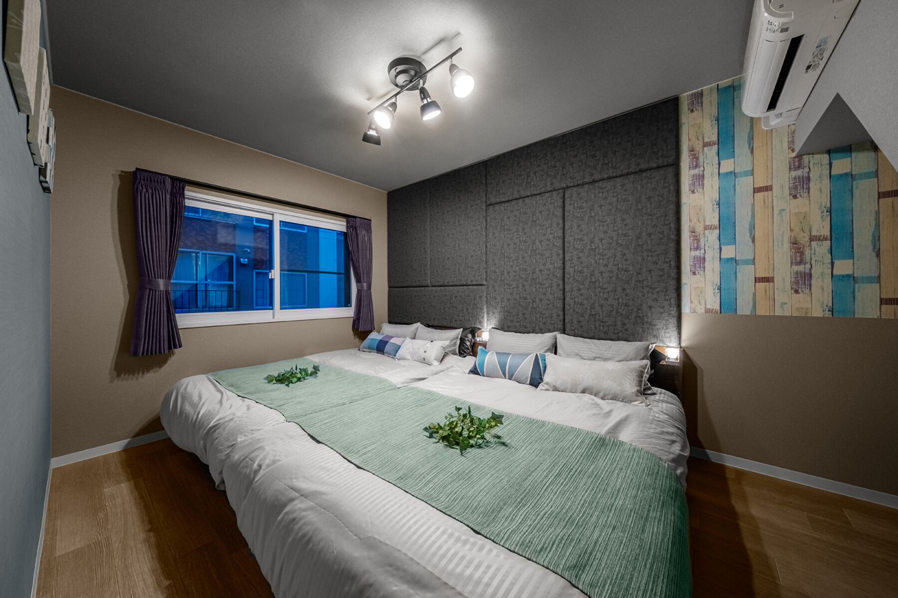 A bedroom with a bed, a window with curtains, a ceiling fan, and an air conditioning unit.