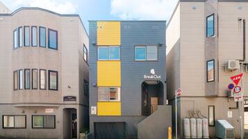 A modern building with a 'BreakOut' sign, featuring a unique facade with yellow and grey panels, a garage entrance, and a fire hydrant nearby.