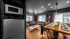 Una cocina moderna con refrigerador y microondas integrados, un comedor con mesa y sillas de madera, y una zona de estar acogedora con sofá y mesa de centro.