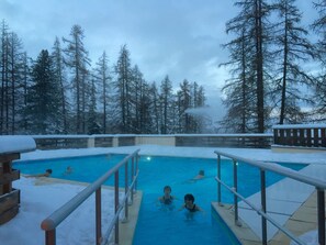 A swimming pool surrounded by snow-covered trees.