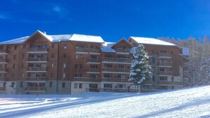 A multi-story building with balconies and a snow-covered landscape. - Residence on the slopes with heated outdoor pool (Vars)