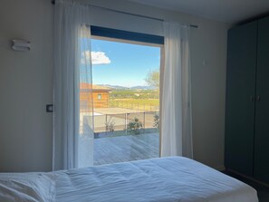 A bedroom with a large window, a bed, and a green wardrobe.