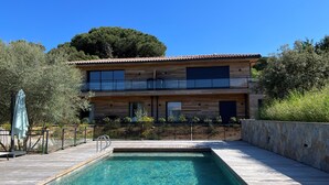 Une maison moderne à deux étages avec une piscine à l’avant.
