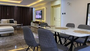 A modern living room with a sofa, a TV, and a dining area with a table and chairs. - A cosy and contemporary 3 bedroom in Ikoyi (Lagos)