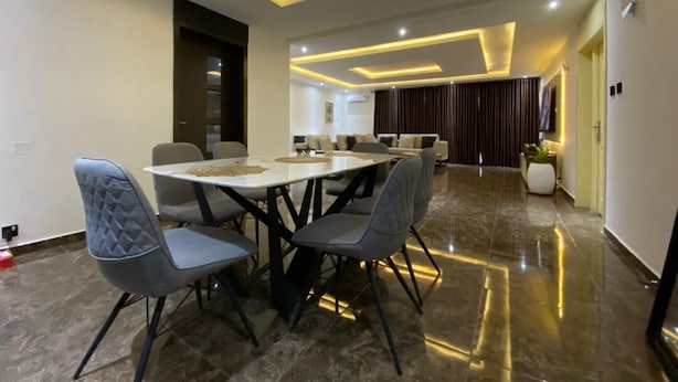 A modern dining area with a rectangular table and four chairs, a ceiling with recessed lighting, and a polished floor. - A cosy and contemporary 3 bedroom in Ikoyi (Lagos)