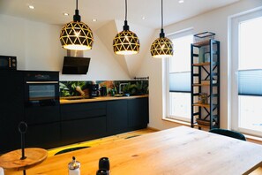 A modern kitchen with a central island, black cabinetry, and pendant lighting. - FeWo26 in Sagenharz | Stylish family apartment, 2 bedrooms, air conditioning, Wi-Fi & Netflix (Thale)