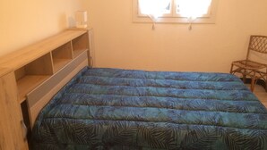 Una stanza con un letto, mensole in legno, una finestra e una sedia.