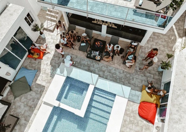 Vista aérea de un área de piscina en la azotea, con varias opciones de asientos y una piscina.