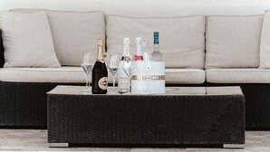 A black wicker coffee table with a bottle of Martini, a glass, and a white container with a gold band. - Luxury Villa in a Private Area (Punta Cana)