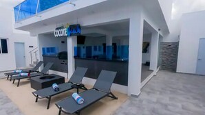 A modern outdoor lounge area with sun loungers and a bar. - Luxury Villa in a Private Area (Punta Cana)