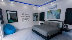 A modern bedroom with a bed, a blue bean bag, and wall art. - Luxury Villa in a Private Area (Punta Cana)