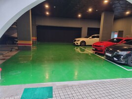 Un estacionamiento con piso verde y tres coches aparcados.