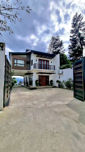 A two-story house with a balcony, a garage, and a view of the sea.