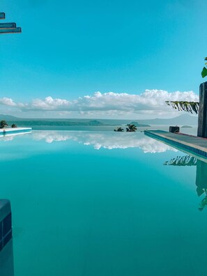 A clear blue pool with a view of distant mountains and clouds.