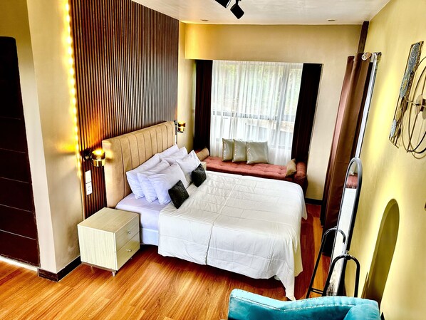 A neatly arranged bedroom with a bed, bedside tables, a chair, and a window with curtains.