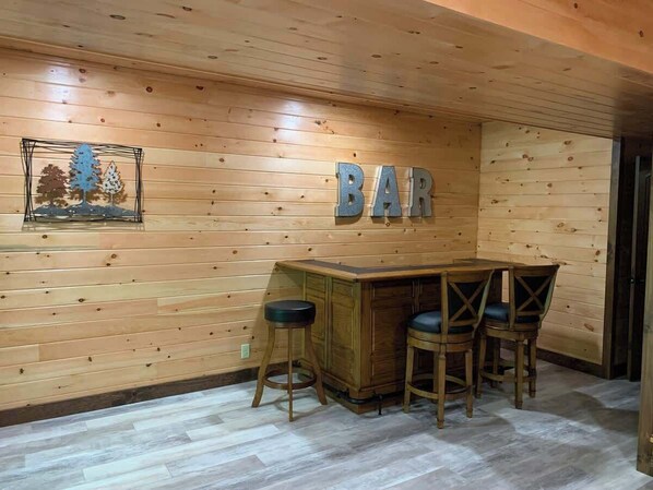 Ein Zimmer mit Holzwänden und einer Bar, inklusive Theke und Hockstühlen.