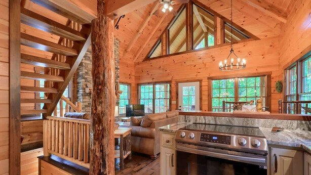 L’intérieur d’une cabane en rondins comprend une cuisine, un coin repas et un escalier.
