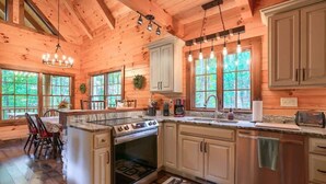 L’intérieur d’une cabane en bois comprend une cuisine dotée d’un grand îlot central, de meubles encastrés et d’un coin repas avec une table et des chaises.