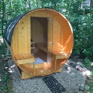 Un sauna en bois doté d’un toit incurvé, d’un banc à l’intérieur et d’une petite table.