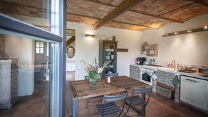 A rustic kitchen with a wooden table, chairs, and a brick ceiling. - Vacation apartment Beelitz - Barn Zauchwitz (Beelitz)