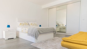 A modern bedroom with a bed, bedside tables, a mirror, and a sliding door closet. - House - Sleeps 3, Free Parking, Garden & Jacuzzi (Calheta)