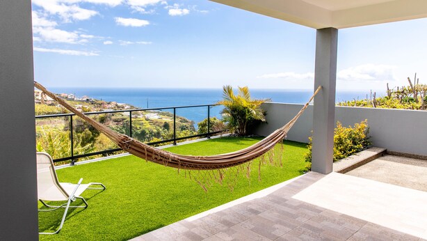 A balcony with a hammock, a chair, and a view of the sea. - House - Sleeps 3, Free Parking, Garden & Jacuzzi (Calheta)