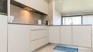A modern kitchen with white cabinets, a built-in oven, and a stainless steel range hood. - House - Sleeps 3, Free Parking, Garden & Jacuzzi (Calheta)