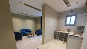 A modern kitchen with a built-in oven and microwave, a dining area with a table and chairs, and a living room with a sofa and a coffee table. - Alfadel Residential Units (Al Baha)