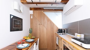 A compact kitchen with a wooden table, white chairs, a microwave, and a coffee maker. - Biennale Gallery Suite (Venezia)