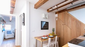 A modern kitchen with a wooden table, white chairs, and a built-in stove. - Biennale Gallery Suite (Venezia)