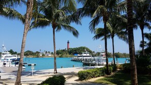 A marina with boats docked, a lighthouse in the background, and palm trees lining the waterfront. - POSHPADZ Presents Villa Tranquila- Private Pool & Tiki Close to Beach Sleeps 10 (Jupiter)