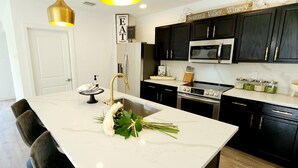 A modern kitchen with a marble island, black cabinets, stainless steel appliances, and a sign reading "Sonoma Valley Winery". - POSHPADZ Presents Villa Tranquila- Private Pool & Tiki Close to Beach Sleeps 10 (Jupiter)