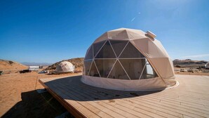 A geodesic dome structure on a wooden deck with a clear sky. - Moon Retreat by Sharjah Collection (Mleiha)