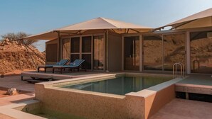 A modern outdoor pool area with lounge chairs and a covered seating area. - Moon Retreat by Sharjah Collection (Mleiha)