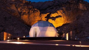 A geodesic dome structure in a desert setting with a rocky backdrop. - Moon Retreat by Sharjah Collection (Mleiha)