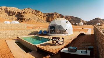 A desert resort with dome-shaped accommodations, a swimming pool, and outdoor seating.