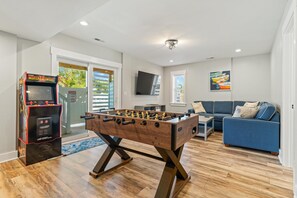 A living room with a foosball table, a sofa, and a television. - Landon Sea: Private Pool, Hot Tub, Dog-Friendly (Corolla)